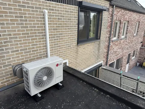 Buitenunit op een plat dak tegen een bakstenen gevel