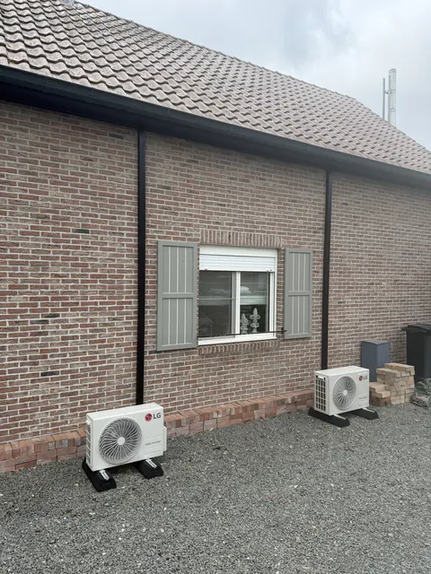 Buitenunit op grind naast een bakstenen woning