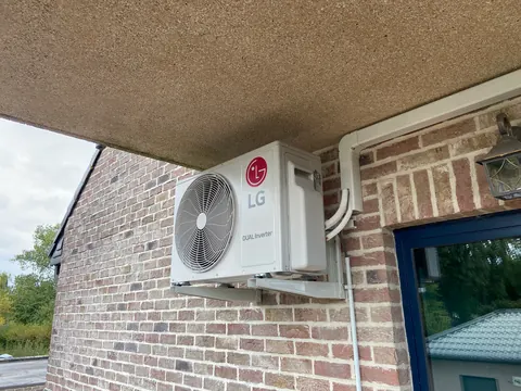 Buitenunit onder een overdekking tegen een bakstenen muur