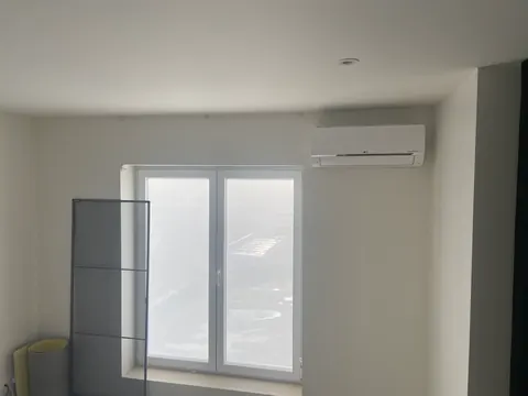 Binnenunit boven een raam in een lichte kamer