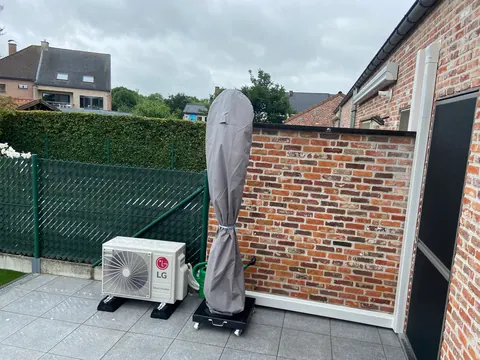 Buitenunit op een terras naast een bakstenen muur