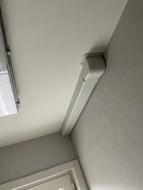 Leiding netjes weggewerkt in een goot in de hoek van het plafond