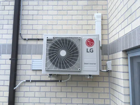 Buitenunit aan een lichte gevel, de leiding in een goot