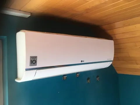Binnenunit aan een blauwgroene muur onder een houten plafond